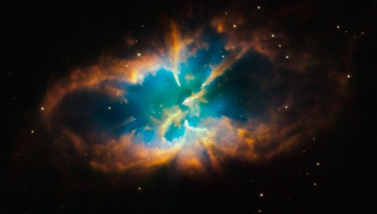 Az NGC 2818A jelű, nyílthalmazba ágyazott planetáris köd. Mindkét objektum kb. 10000 fényév távolságban van a Pyxis (Tájoló) csillagképben. A hamisszínes felvételen gázok emisszióját örökítették meg: a vörös nitrogént, a zöld hidrogént, míg a kék oxigént jelöl. [NASA, ESA, Hubble Heritage Team (STScI/AURA)]