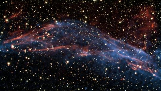 Az RCW 86 katalógusjelű szupernóva-maradvány északkeleti részének montázsképe. Vörös szín kódolja a VLT FORS2 műszerével Hα keskenysávú szűrőn keresztül rögzített adatokat, míg a kék szín a Chandra röntgenadatait. Ebben a tartományban nagyenergiájú elektronok szinkrotronsugárzása dominál.<br />
[ESO/E. Helder & NASA/Chandra]